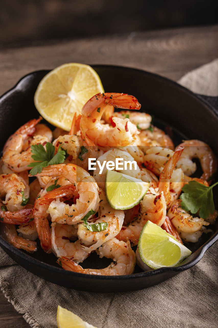 food and drink, food, healthy eating, citrus fruit, shrimp, fruit, lemon, dish, freshness, seafood, herb, produce, crustacean, wellbeing, scampi, vegetable, studio shot, no people, cuisine, slice, meal, wood, spice, prawn, animal, rustic, lime, paella, indoors, meat, fish, table, dark, kitchen utensil, pan, cooking pan, close-up, savory food, dinner, household equipment, citrus, fried, gourmet