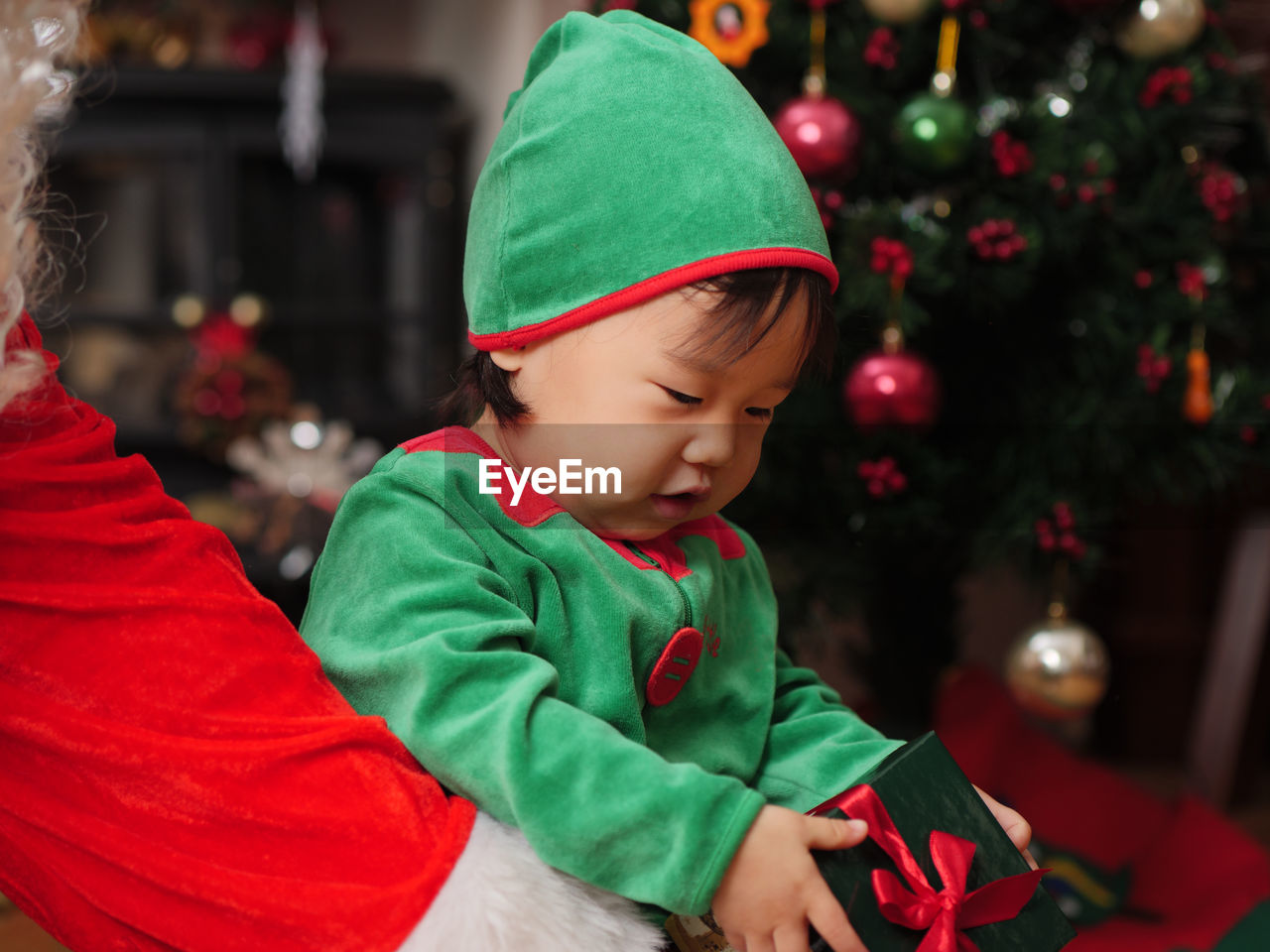 Close-up of baby girl and santa claus with christmas gift at home