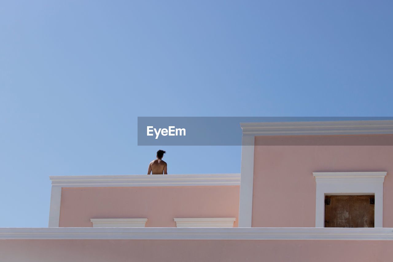 Low angle view of man on terrace against clear sky