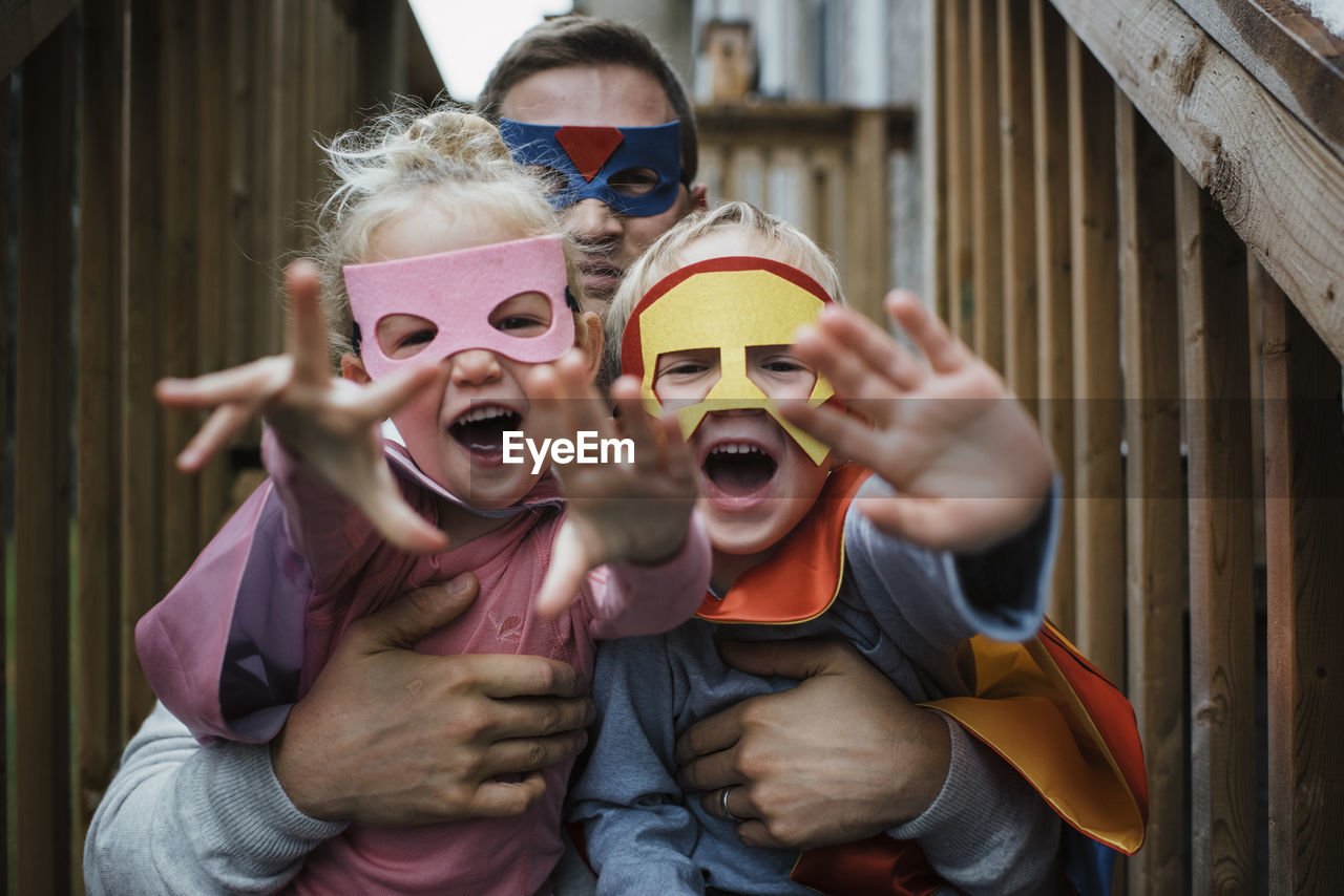 Portrait of children with father in superhero costumes