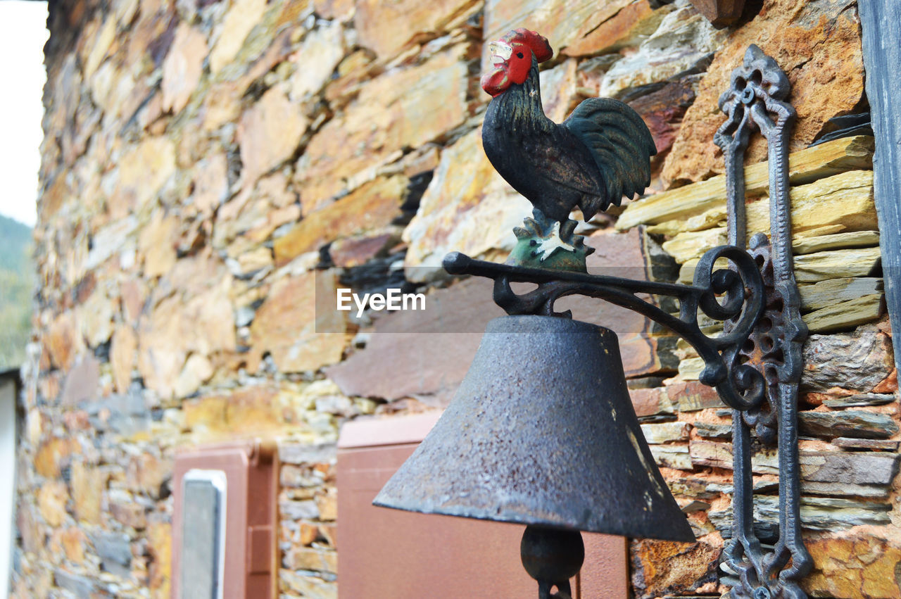 Close-up of antique metallic bell on stone wall