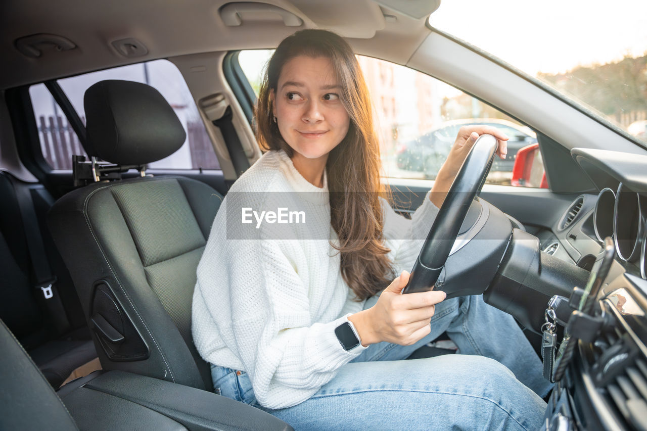 portrait of young woman using mobile phone while sitting in car