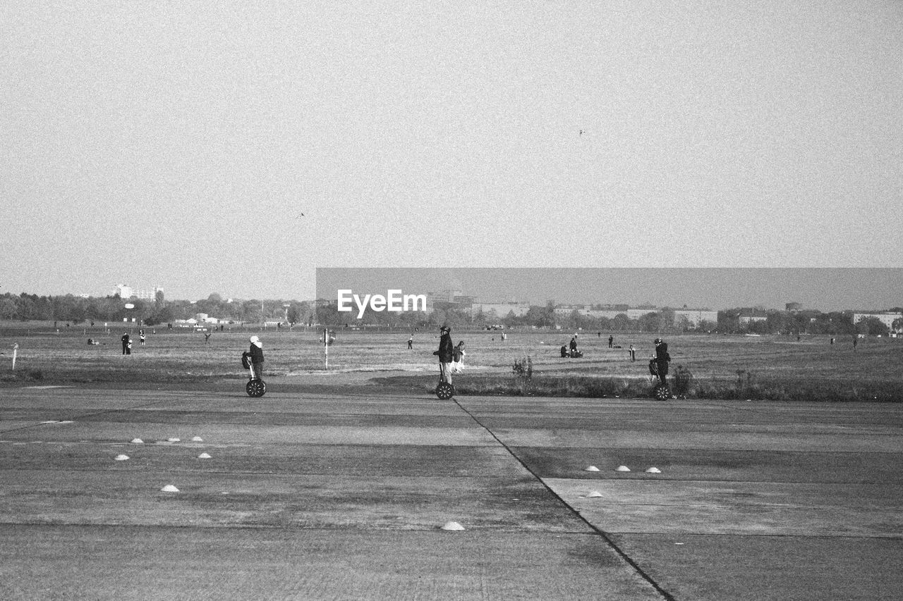 People riding segways against clear sky