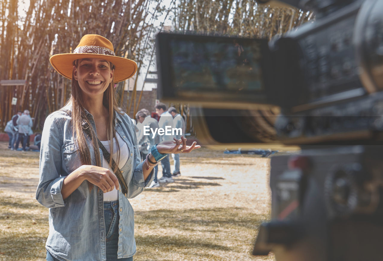 Exterior shot of young beautiful woman vlogging, happy smiling young vlogger possing on the camera.