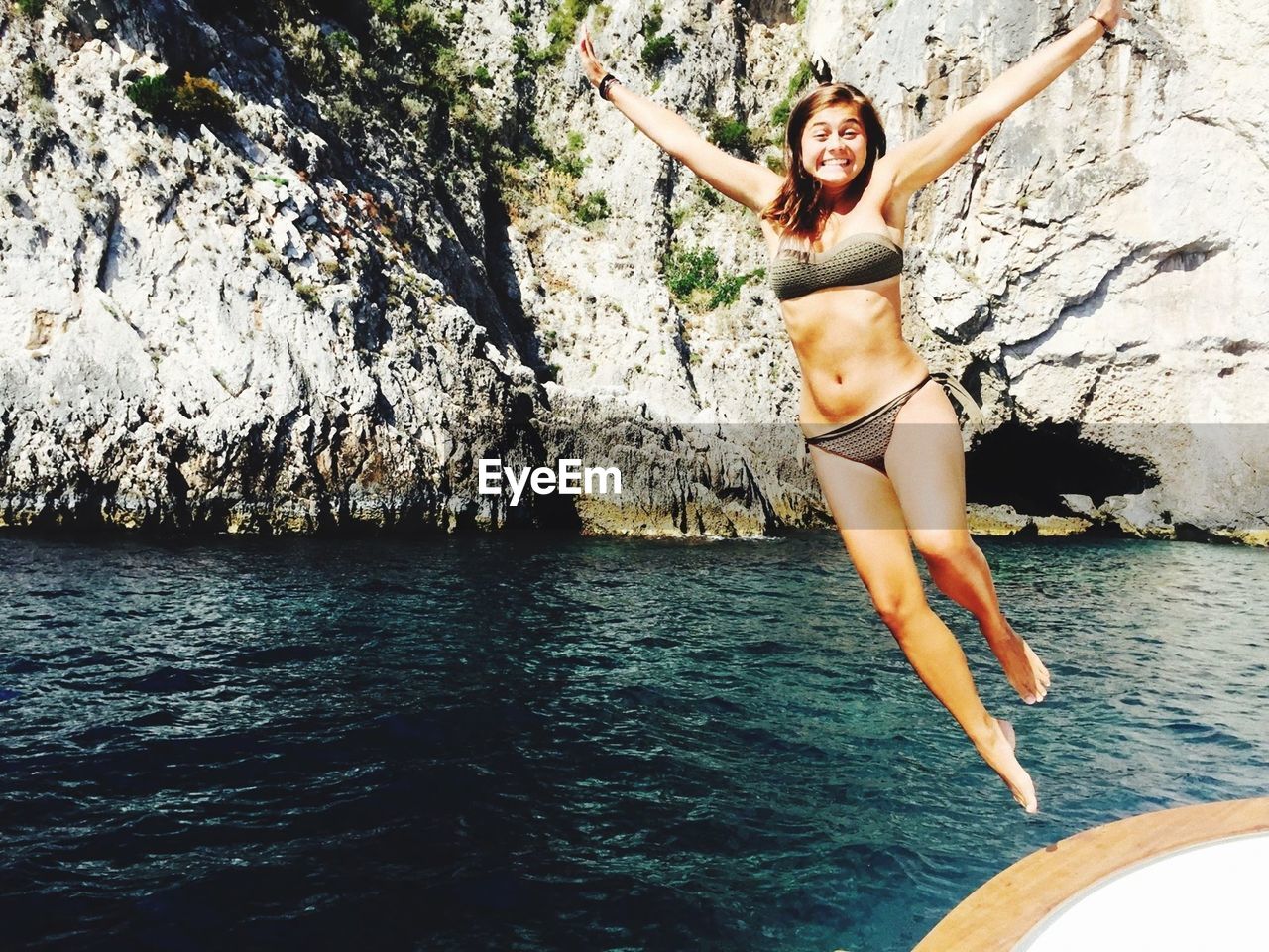 Young woman wearing bikini while jumping in sea