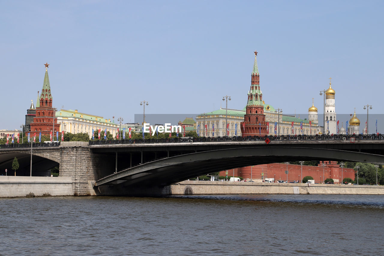 BRIDGE OVER RIVER BY BUILDINGS AGAINST SKY