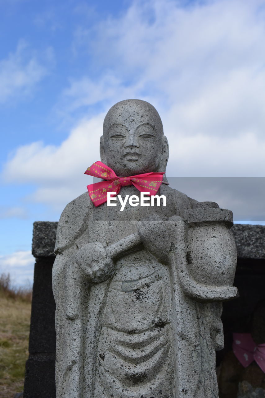 CLOSE-UP OF STATUE AGAINST SKY AND CLOUDS