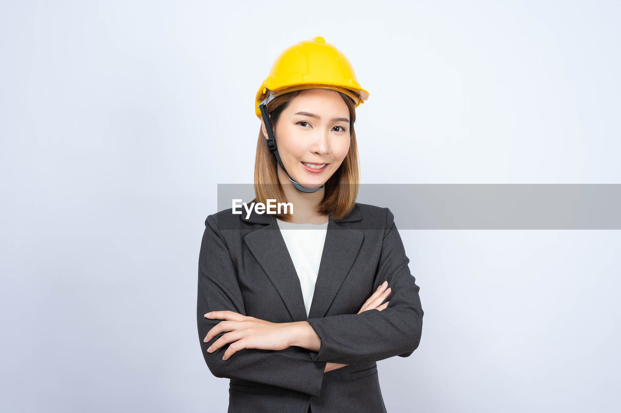 PORTRAIT OF A SMILING WOMAN AGAINST WHITE BACKGROUND