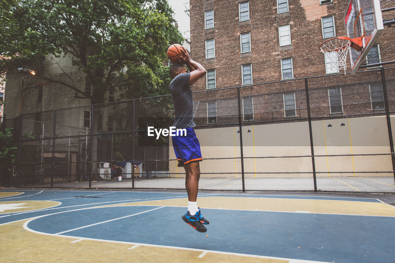 Young man practicing basketball in court