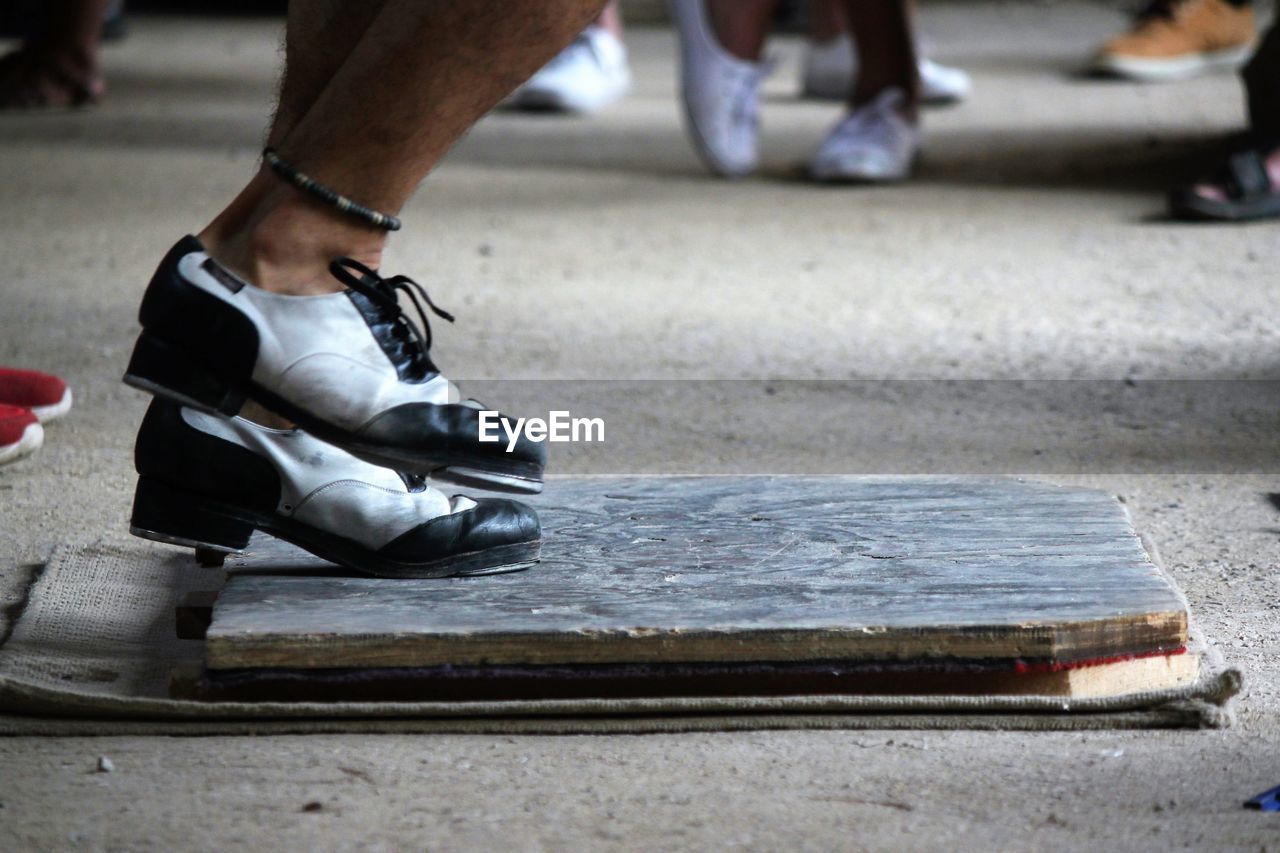 Low section of man tap dancing on wood