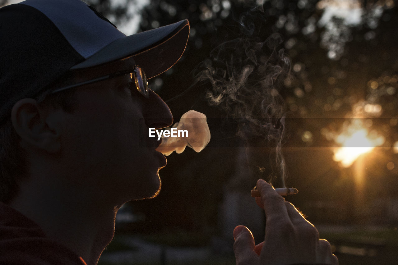 Side view of man smoking cigarette during sunset