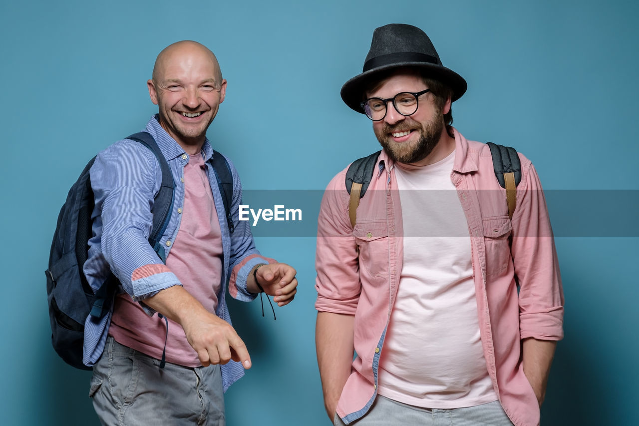 Portrait of friends standing against blue background