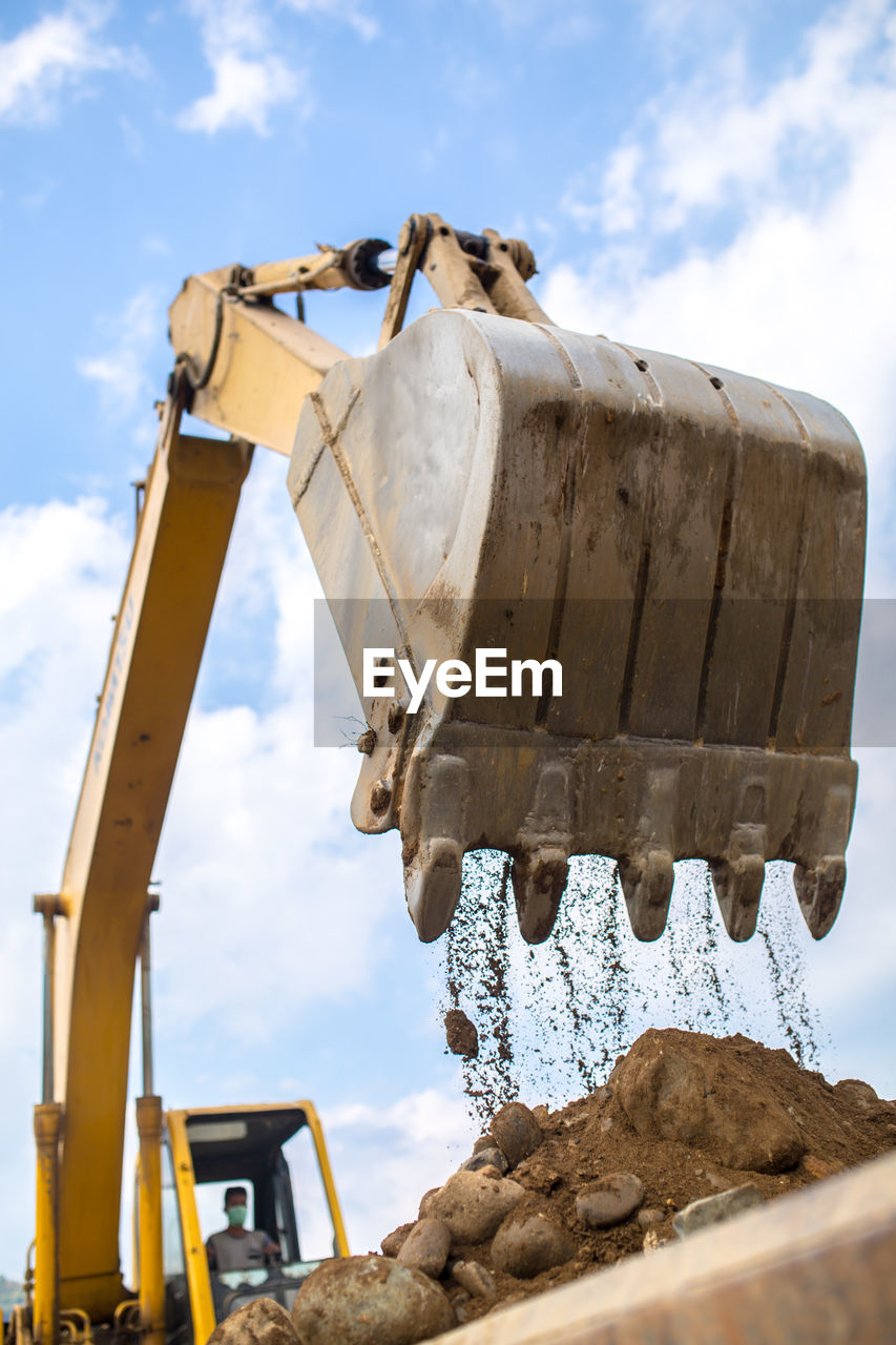 LOW ANGLE VIEW OF MACHINE PART AGAINST CLOUDY SKY