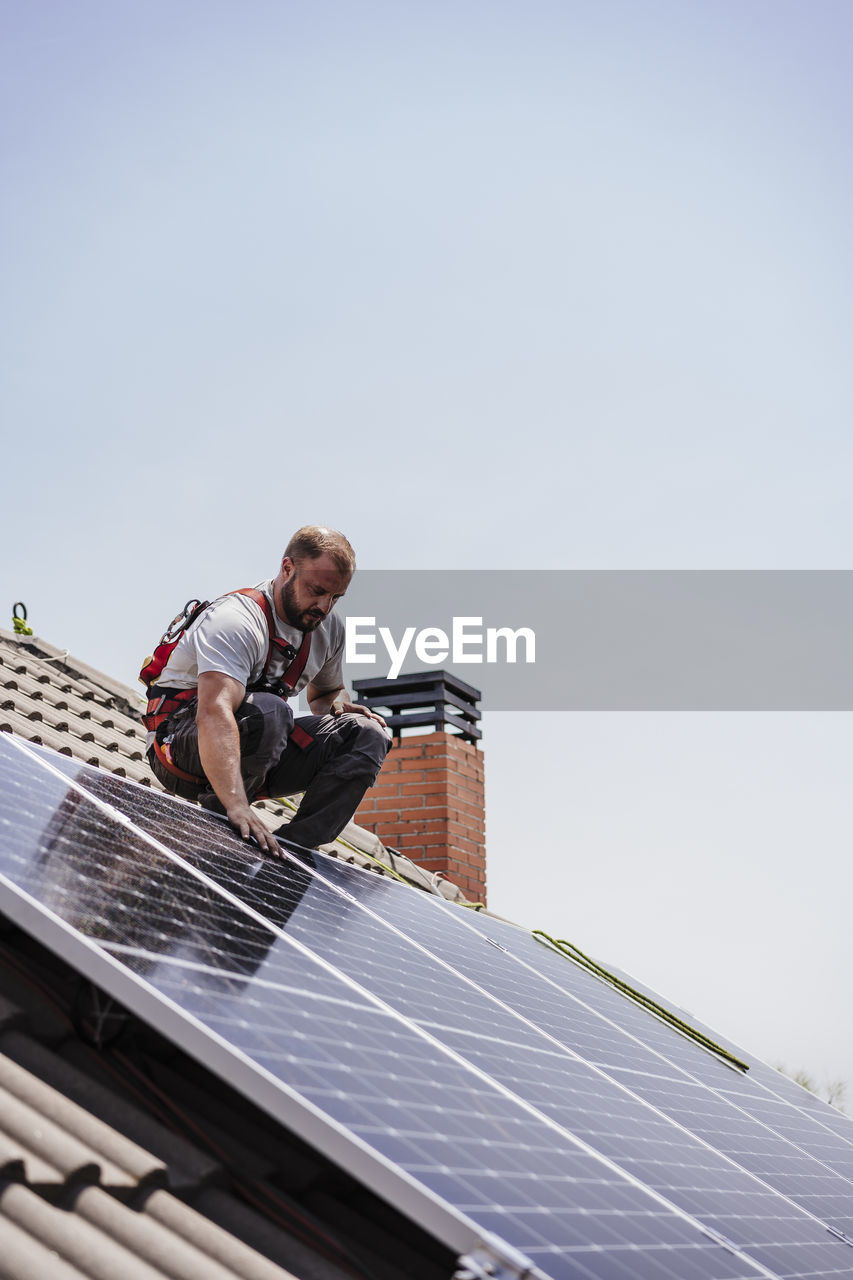 Electrician installing solar panels on roof