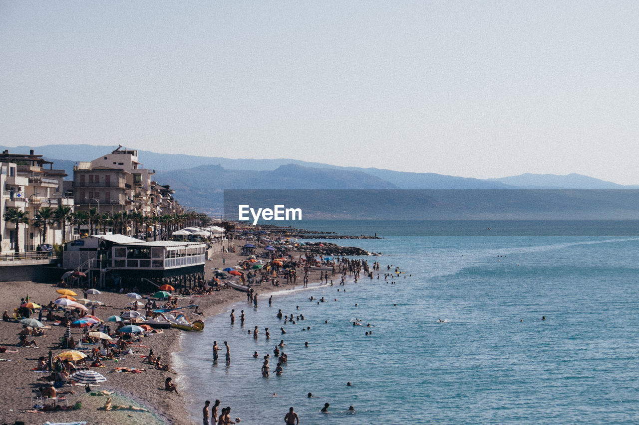 GROUP OF PEOPLE ON BEACH AGAINST SKY