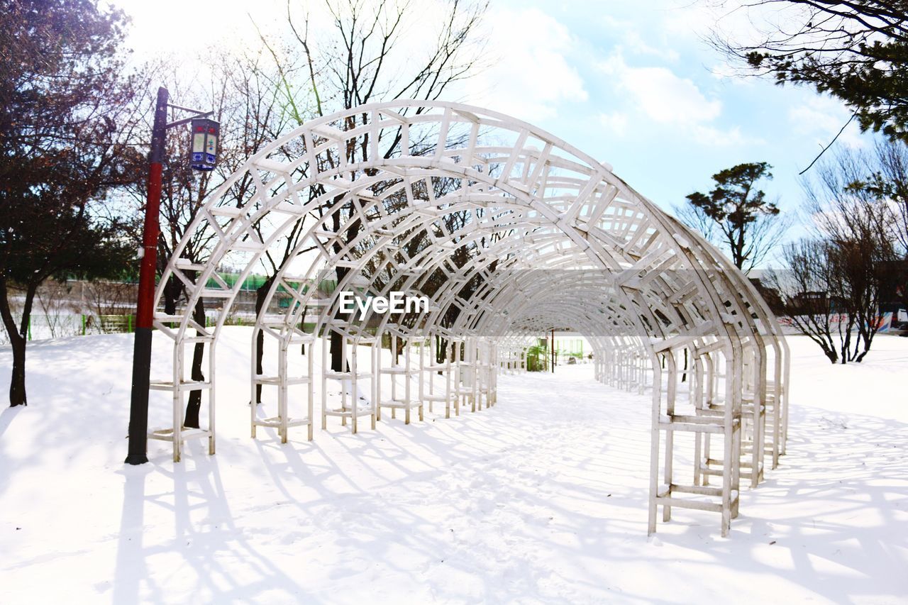 Arch structures on snow covered field against sky