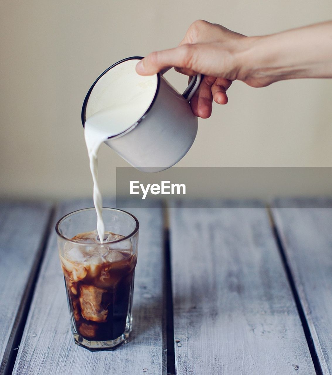 Close-up of hand pouring coffee in glass on table