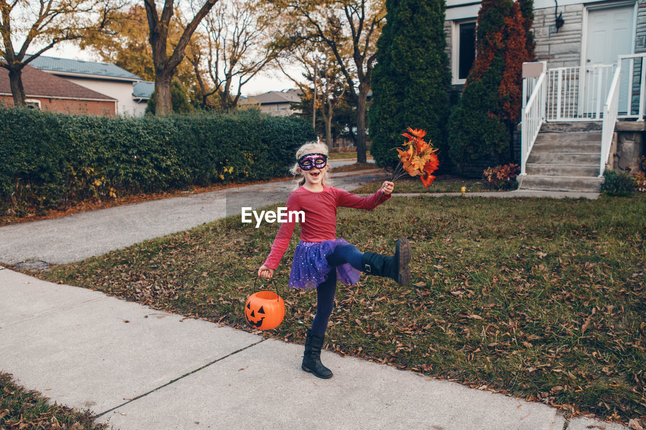 Full length of girl wearing mask standing in front of house