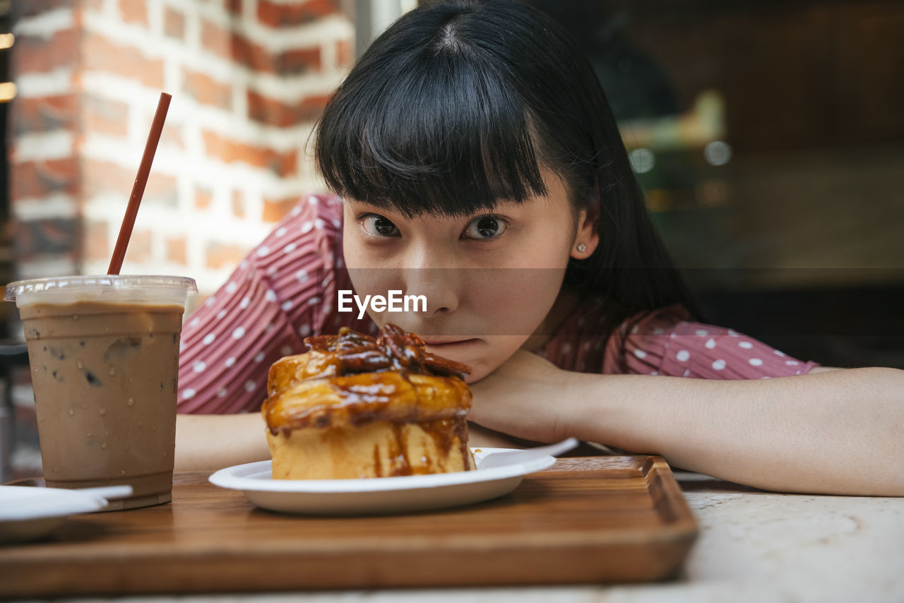 Portrait of young woman by food in cafe