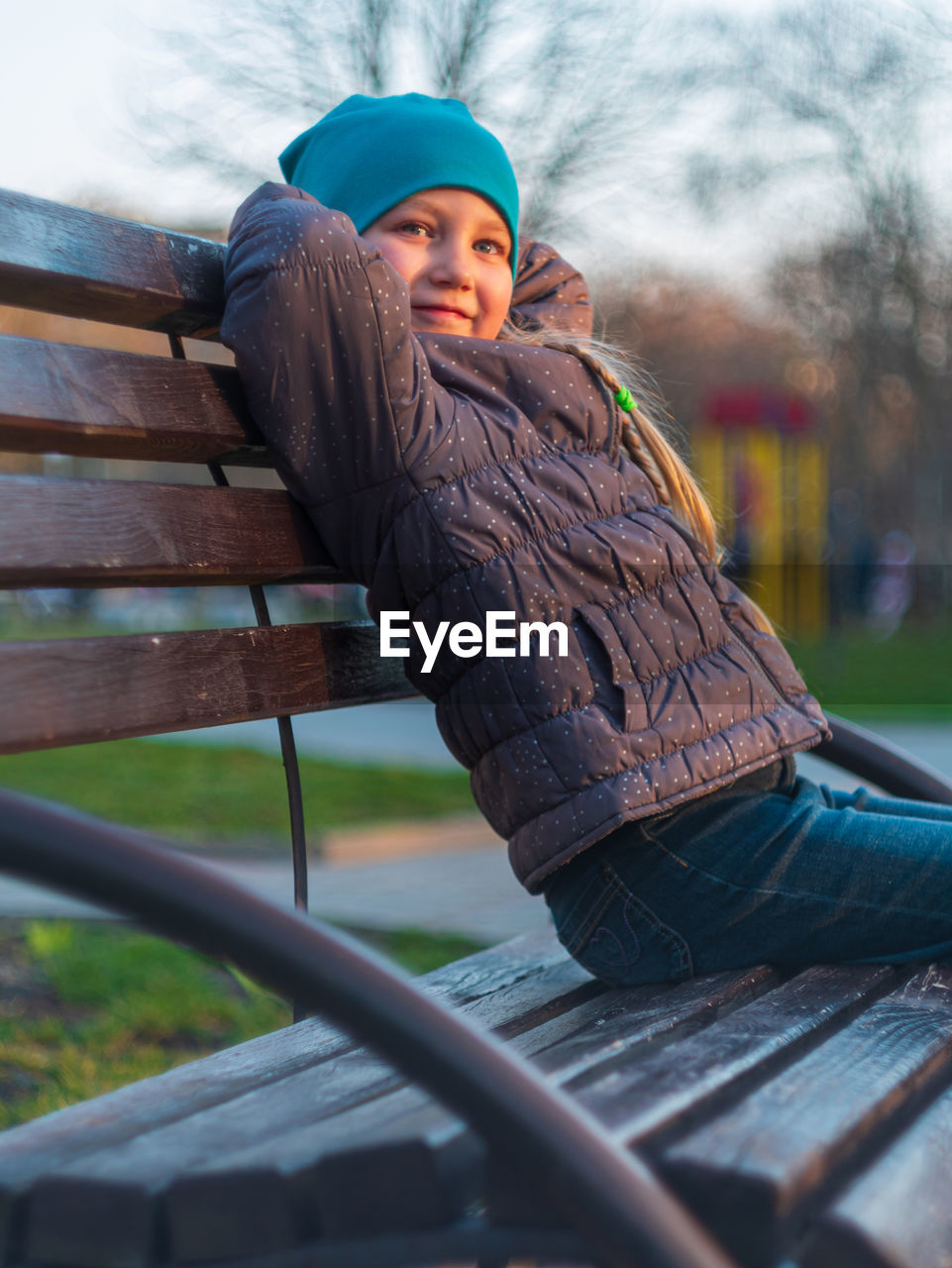 PORTRAIT OF GIRL SITTING ON BENCH AGAINST WALL