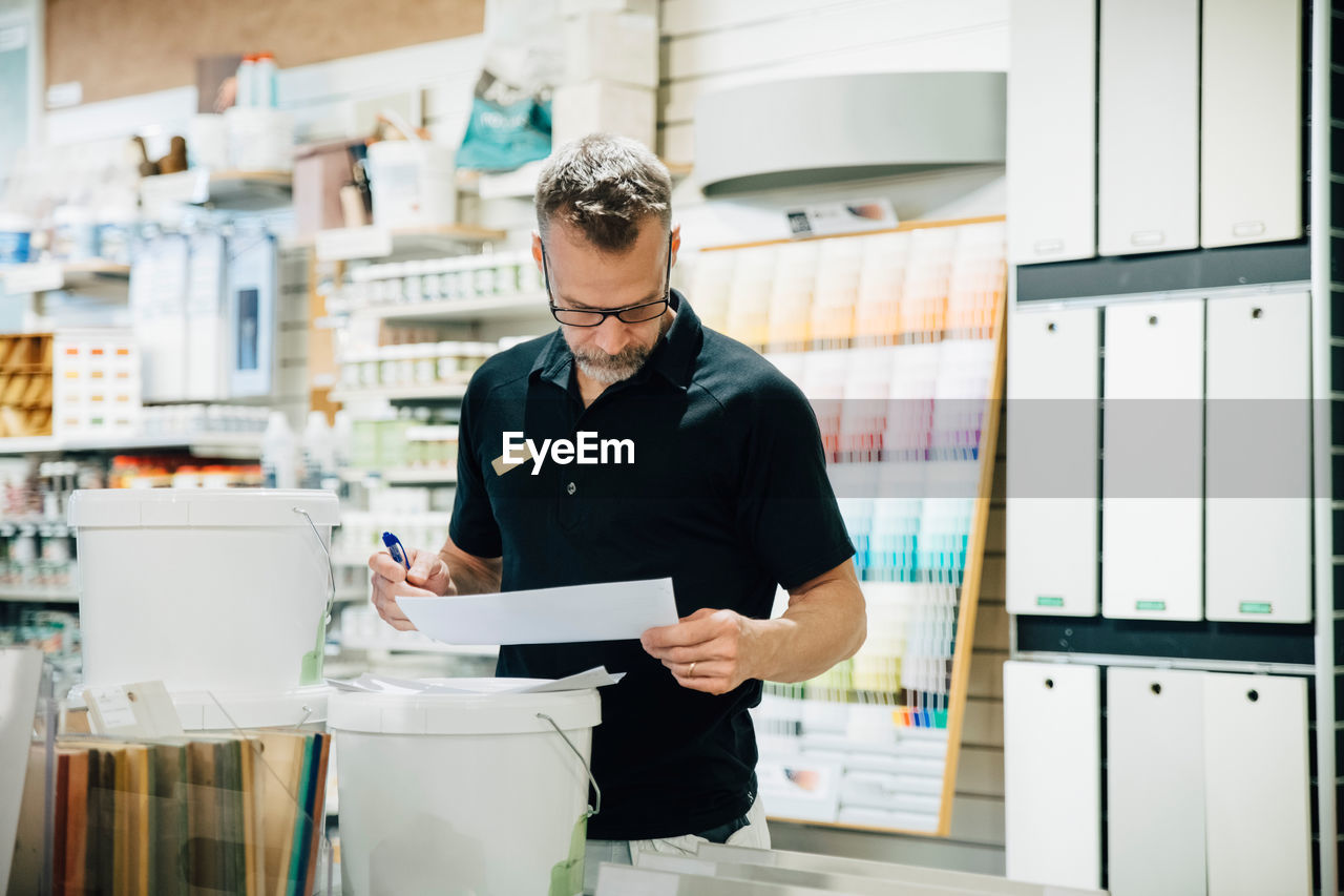 Mature male employee reading document in hardware store