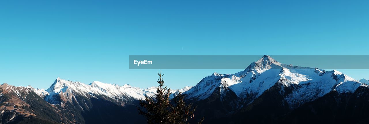 LOW ANGLE VIEW OF SNOWCAPPED MOUNTAINS AGAINST BLUE SKY