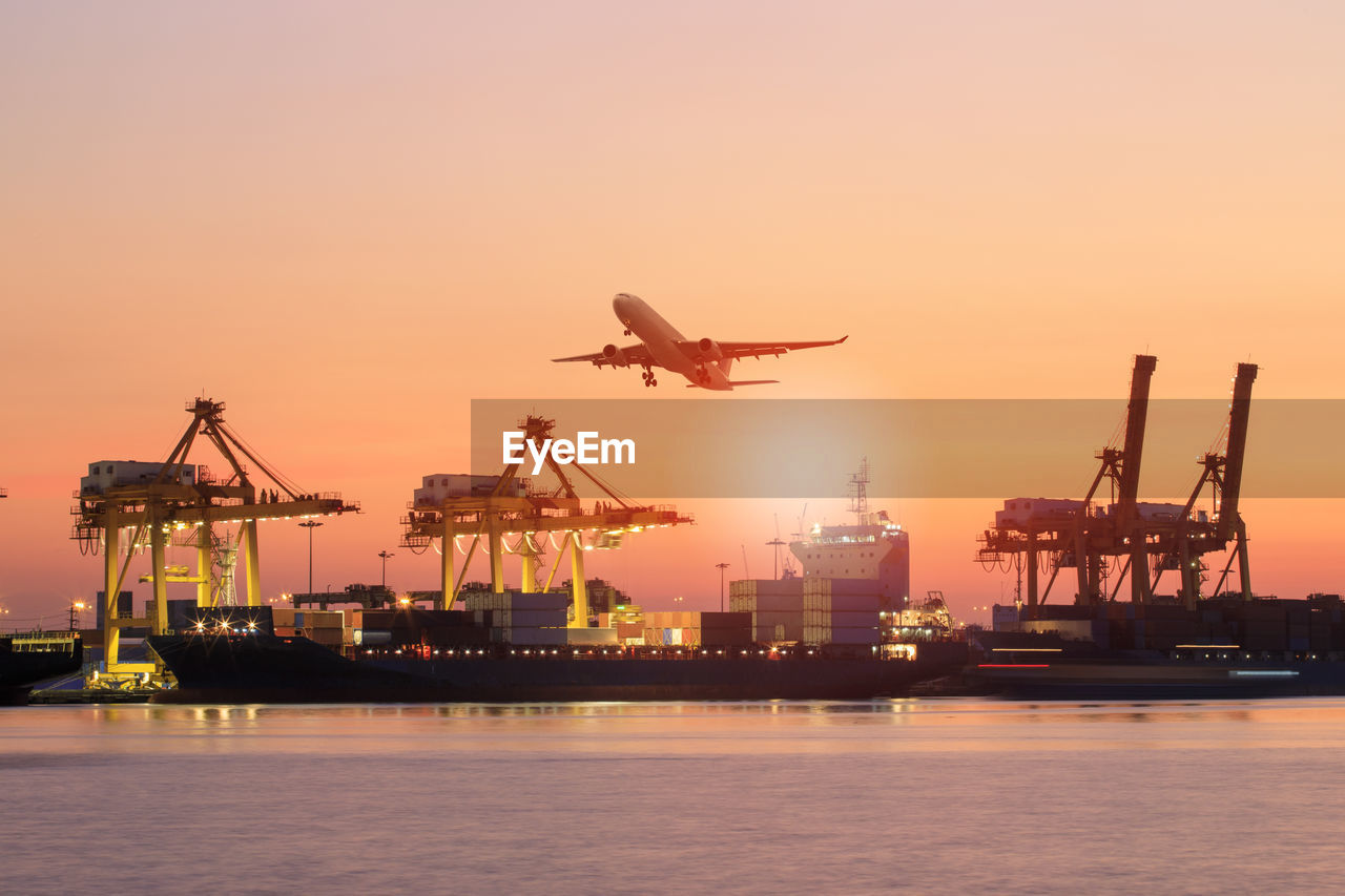 Shipping boat and cargo plane flying against beautiful sky