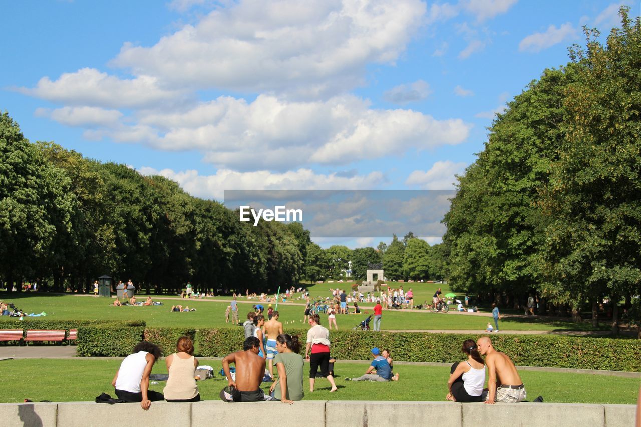 People sitting in park against sky