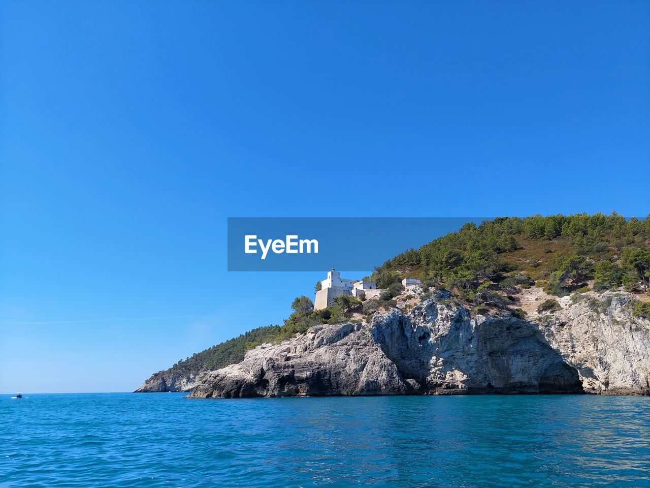 SEA BY ROCKS AGAINST CLEAR BLUE SKY