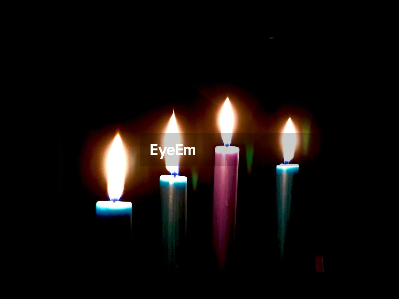 CLOSE-UP OF LIT CANDLES IN DARK