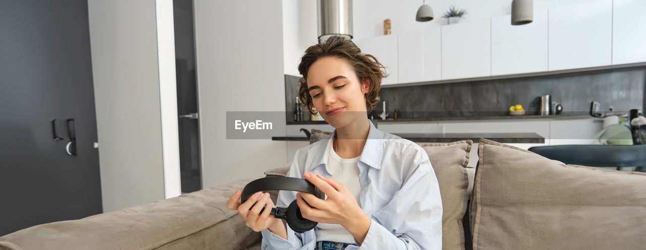 young woman using phone while sitting on sofa