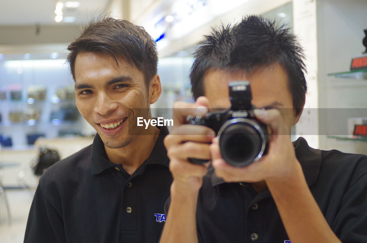 CLOSE-UP PORTRAIT OF SMILING MAN WITH CAMERA