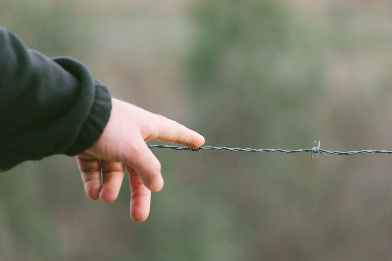 Cropped hand touching barbed wire