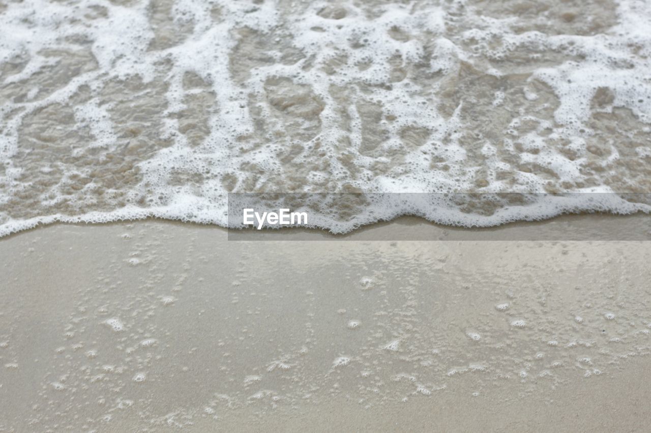 CLOSE-UP OF WAVE ON SAND AT BEACH