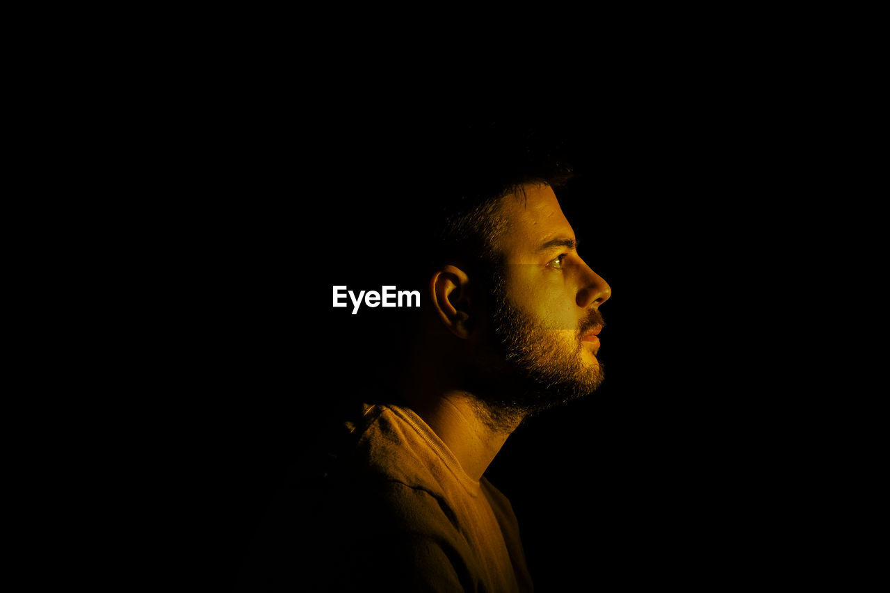 Portrait of young man against black background