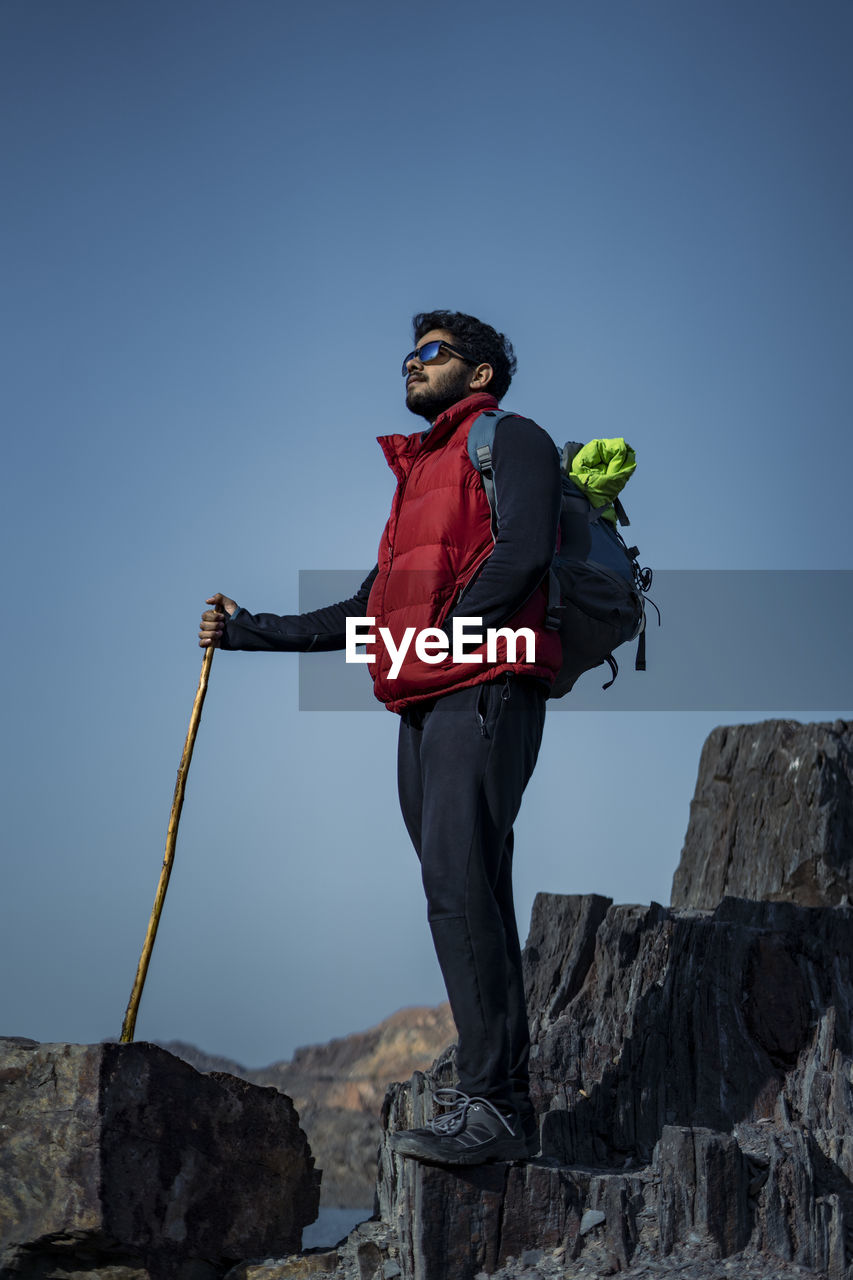 LOW ANGLE VIEW OF MAN STANDING ON ROCK