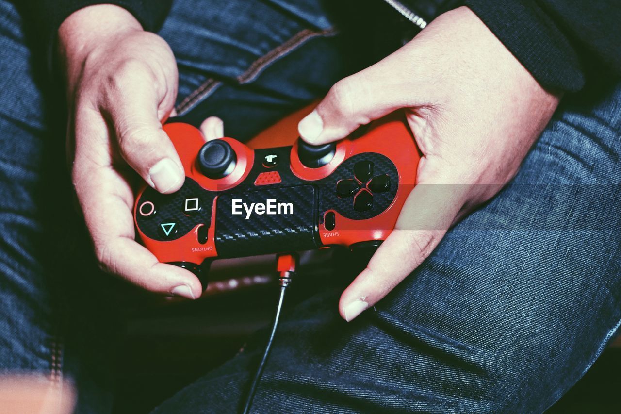 Midsection of man holding video game remote control