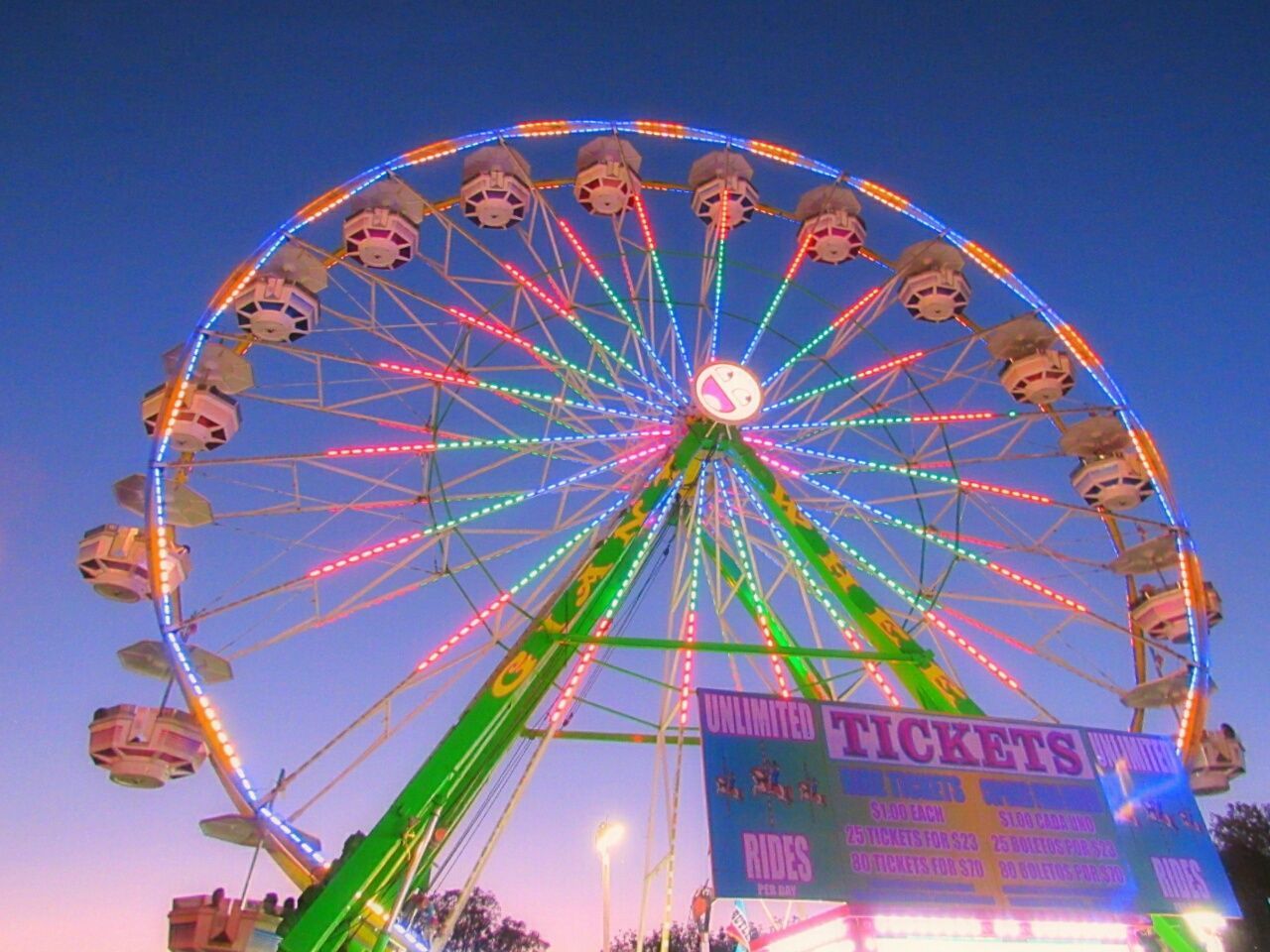 LOW ANGLE VIEW OF ILLUMINATED FERRIS WHEEL AGAINST BLUE SKY