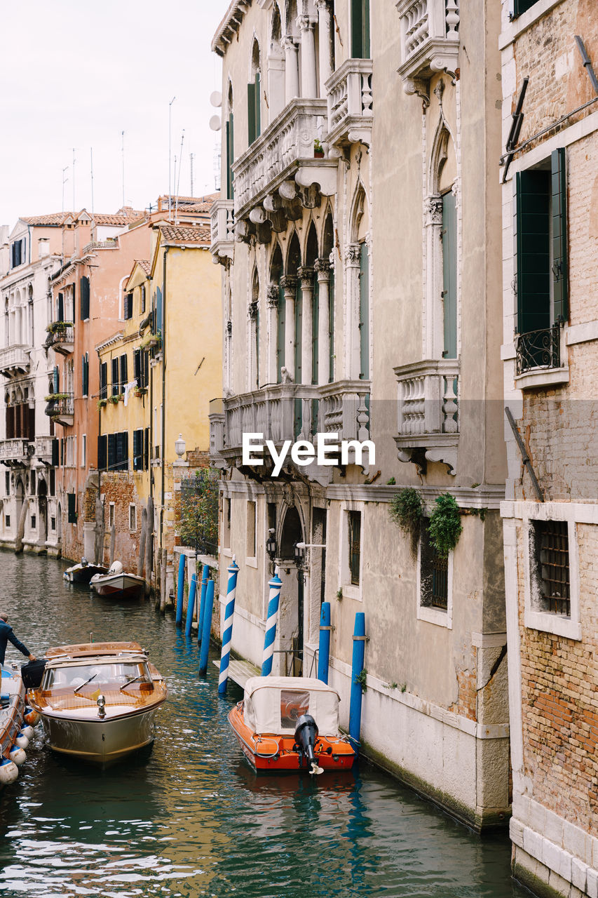 Boats moored in canal amidst buildings in city