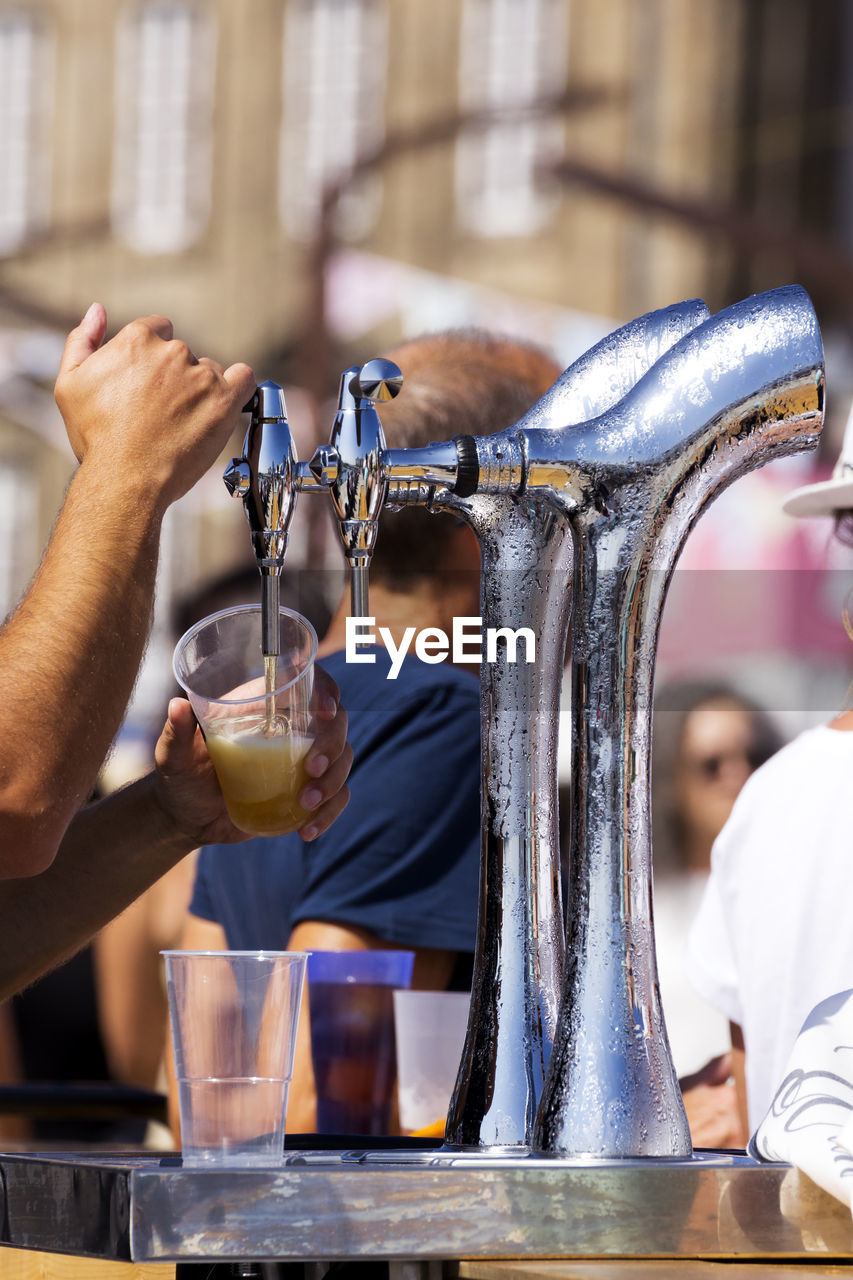 Barman serving draft beer pouring in street fest with people on background