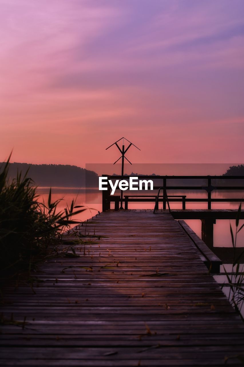 Silhouette pier over lake against sky during sunset