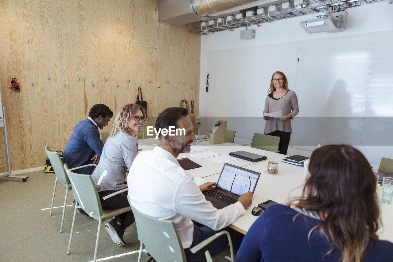 Smiling male and female business colleagues sharing ideas in office meeting