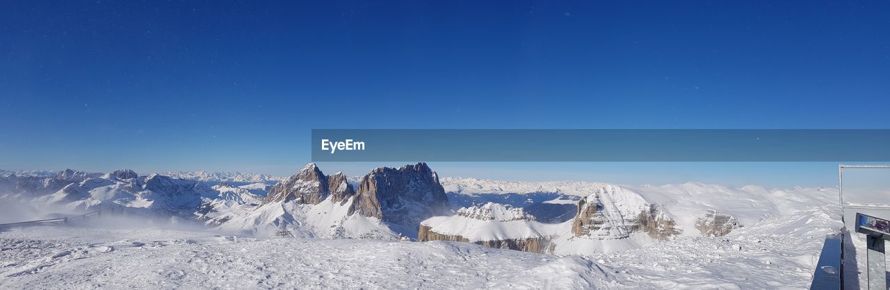 Panoramic view of snow covered landscape against clear blue sky