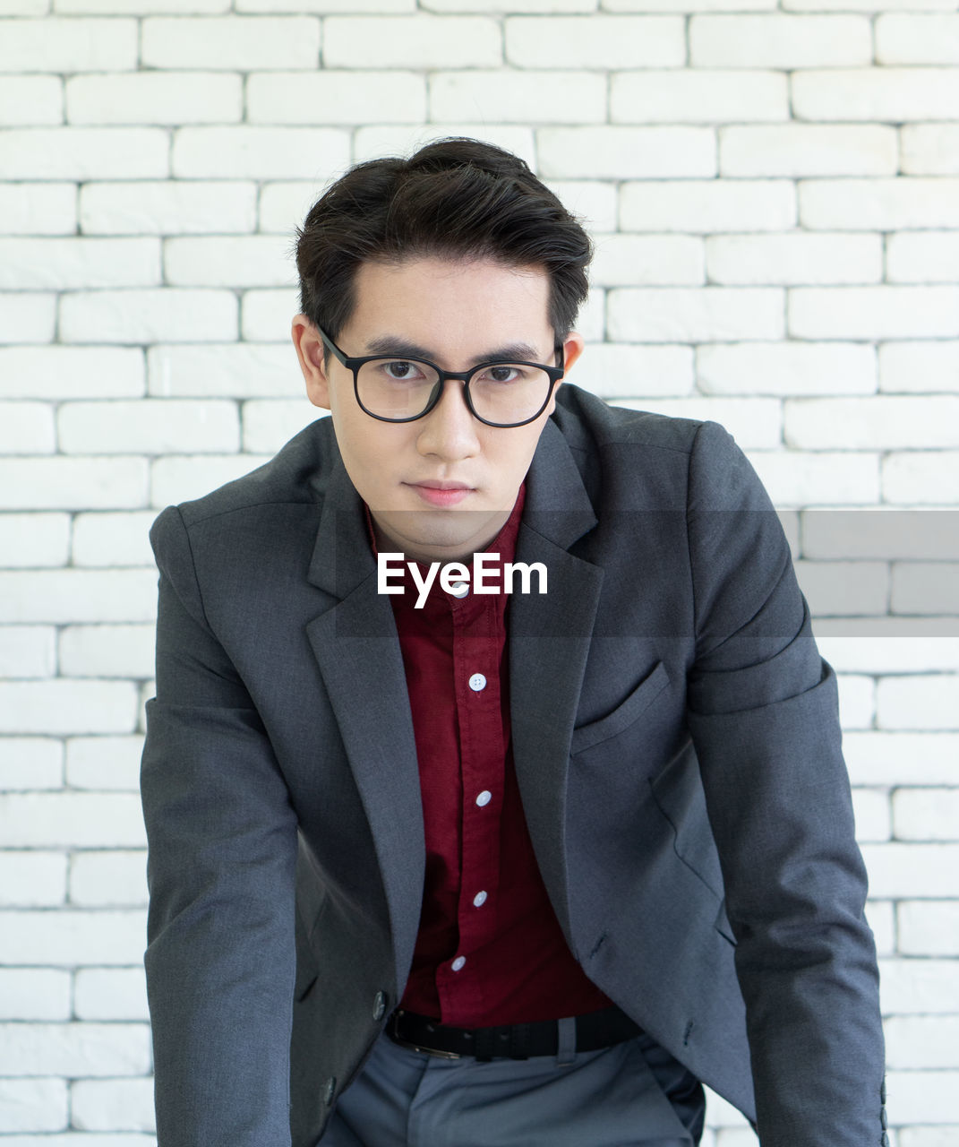 Portrait of young businessman standing against wall