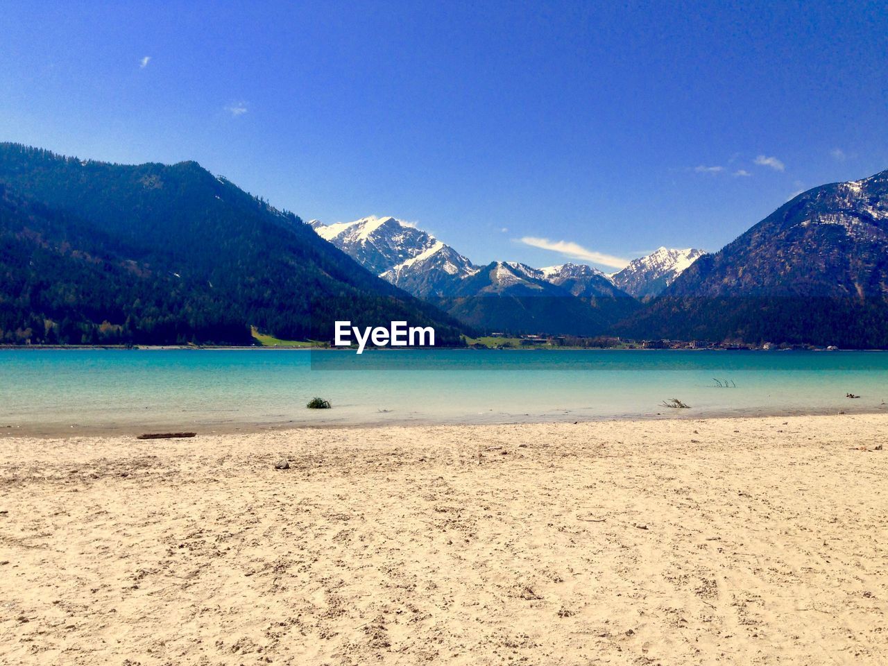 Scenic view of sea and mountains against clear blue sky