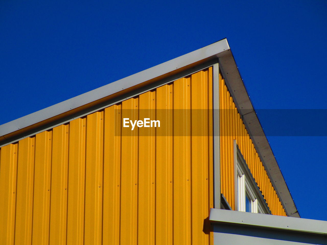 LOW ANGLE VIEW OF YELLOW BUILDING AGAINST BLUE SKY