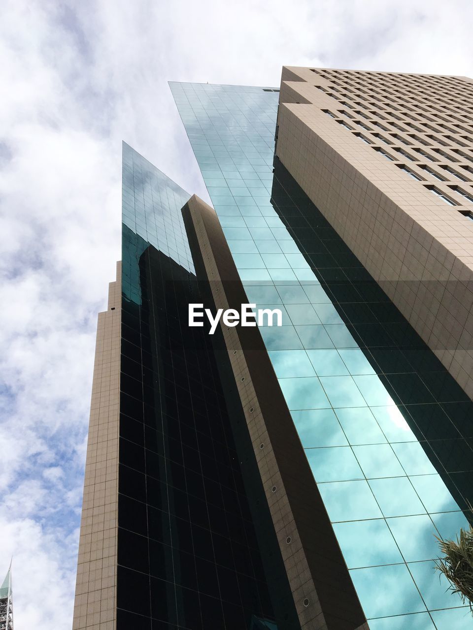 LOW ANGLE VIEW OF MODERN GLASS BUILDING AGAINST SKY