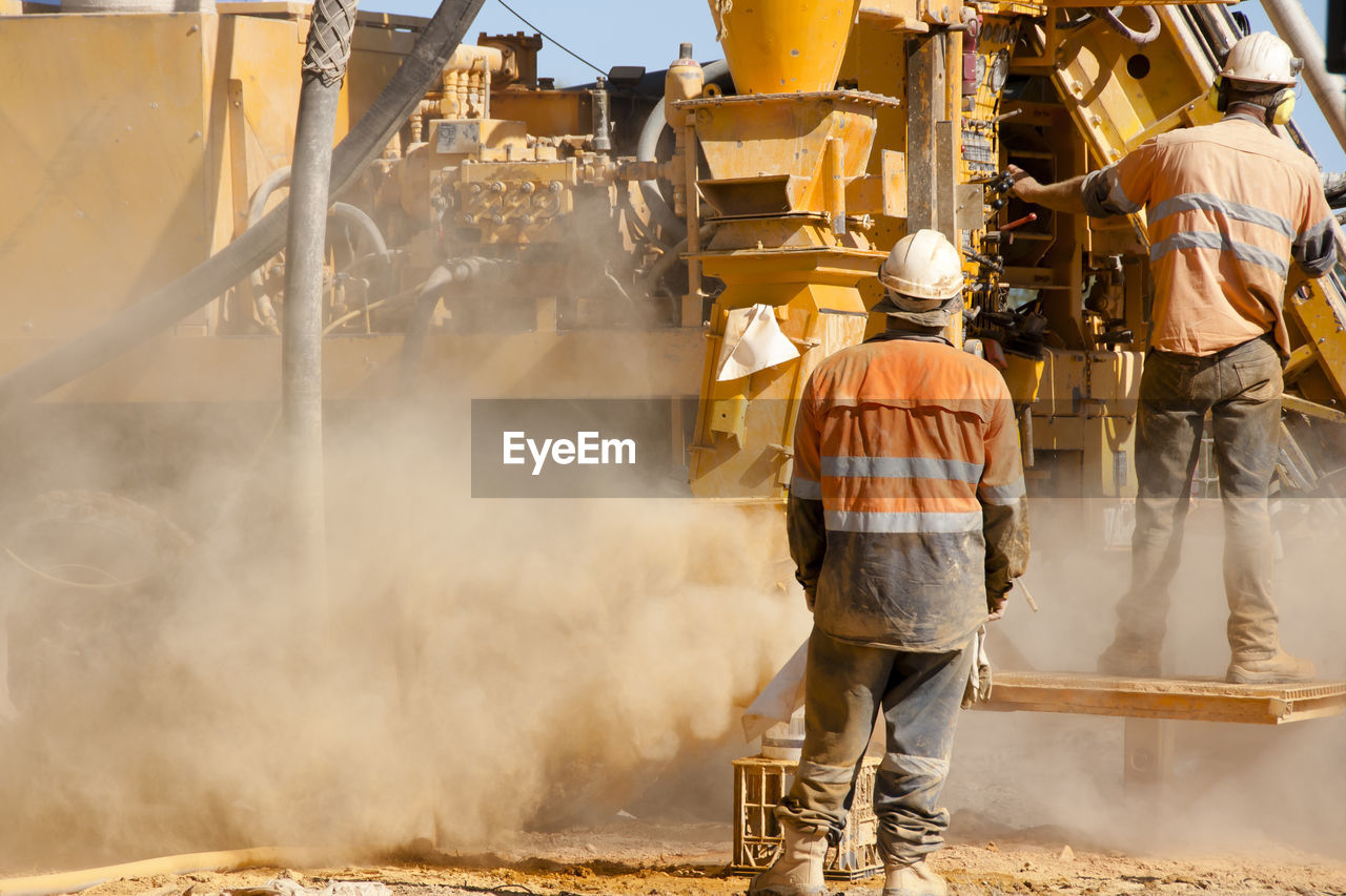 REAR VIEW OF PEOPLE WORKING ON CONSTRUCTION SITE