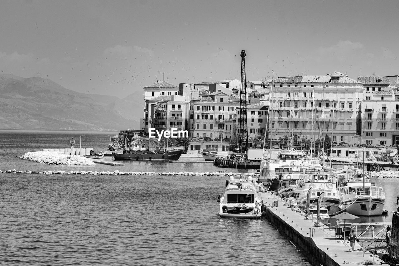 water, nautical vessel, transportation, mode of transportation, architecture, black and white, sea, building exterior, vehicle, ship, built structure, sky, monochrome photography, nature, monochrome, city, watercraft, harbor, travel, building, dock, travel destinations, boat, day, port, no people, moored, coast, land, beach, waterfront, cityscape, ferry, outdoors, tourism, pier, waterway, sailboat