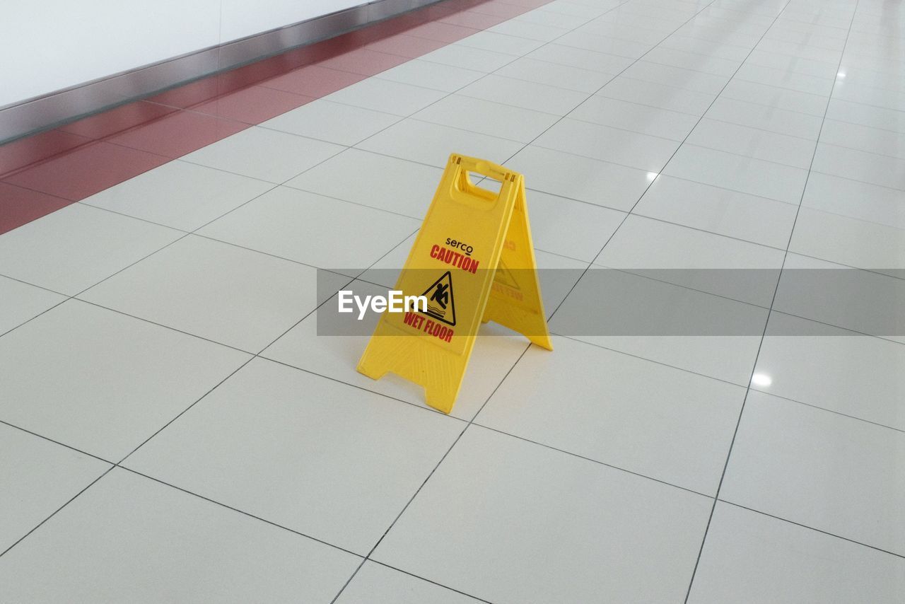 High angle view of warning sign on tiled floor